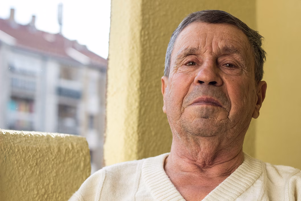 Photo of a man in a cream pullover in front of a butter yellow wall