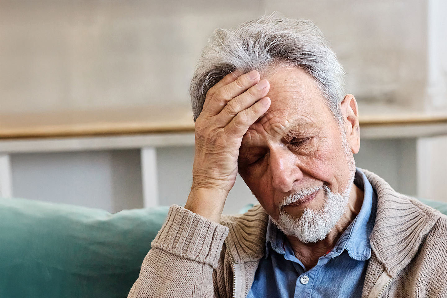 Photo of a bearded man with hand on his forehead