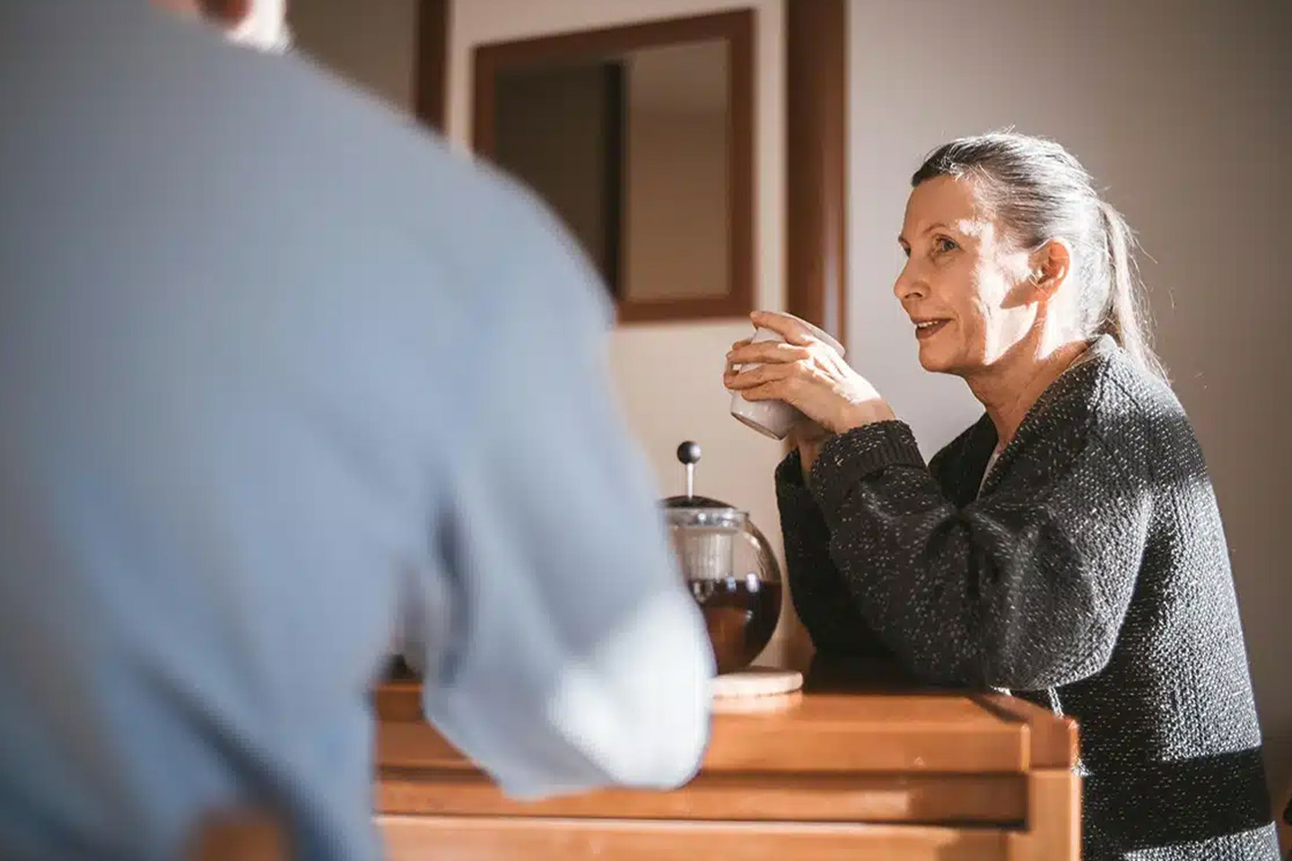 Photo of a woman in a charcoal knit holding a cup