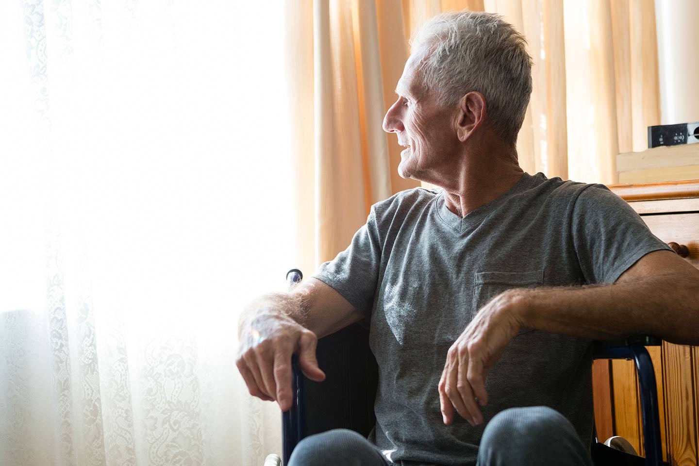 Photo of a man in a t shirt looking out a window