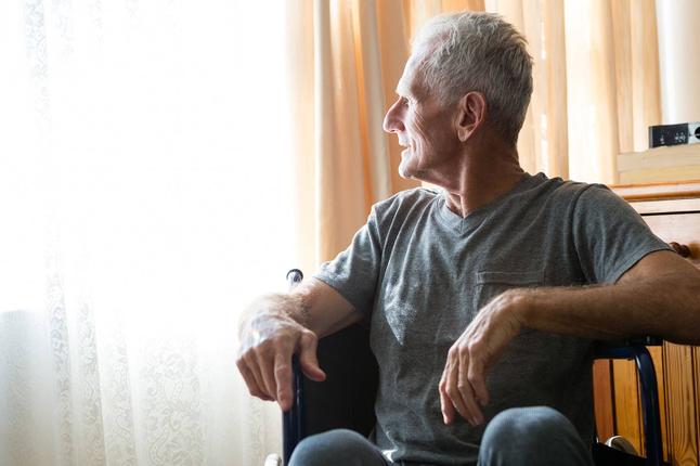 Photo of a man in a t shirt looking out a window