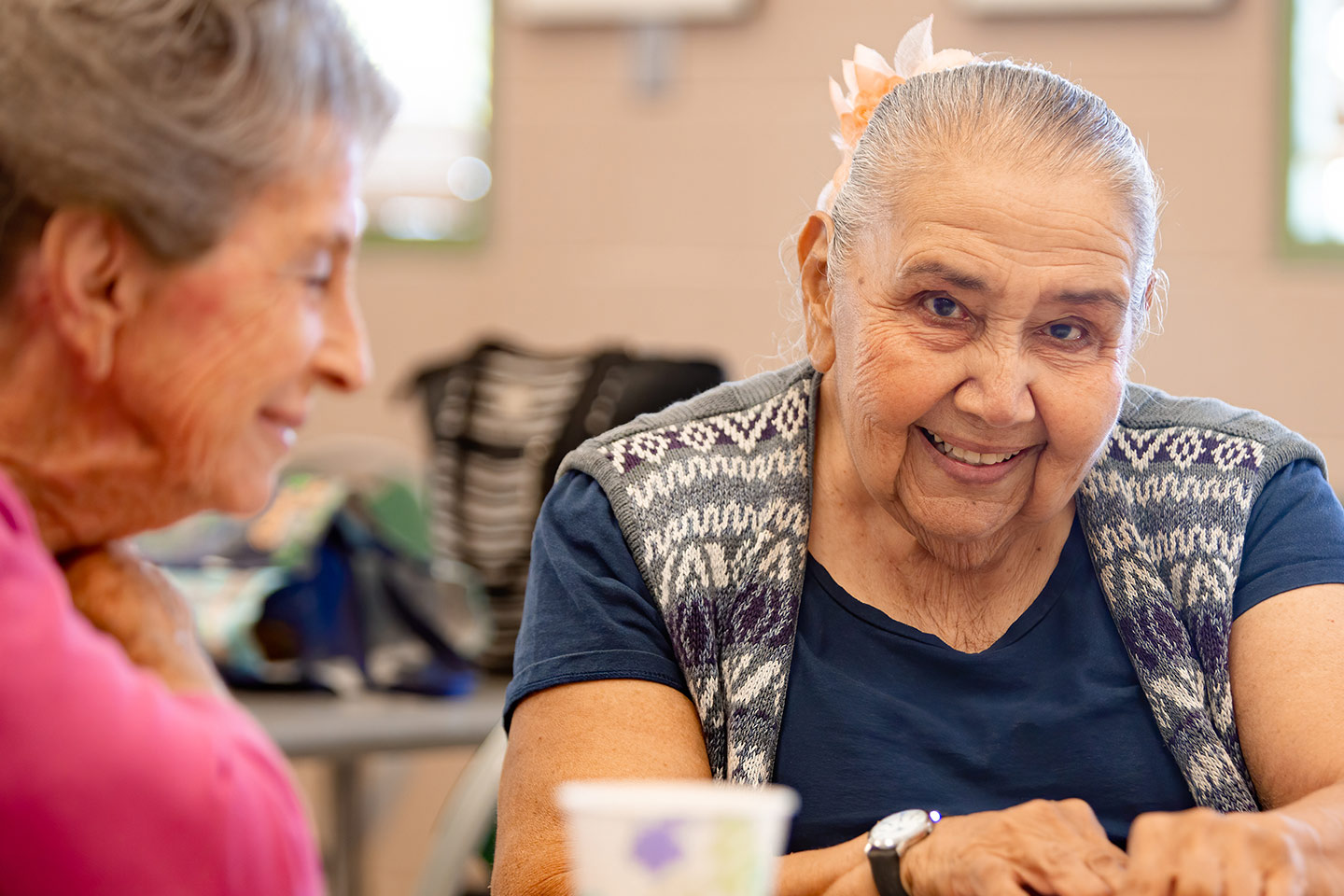Photo of a smiling woman seated next to a lady in pink