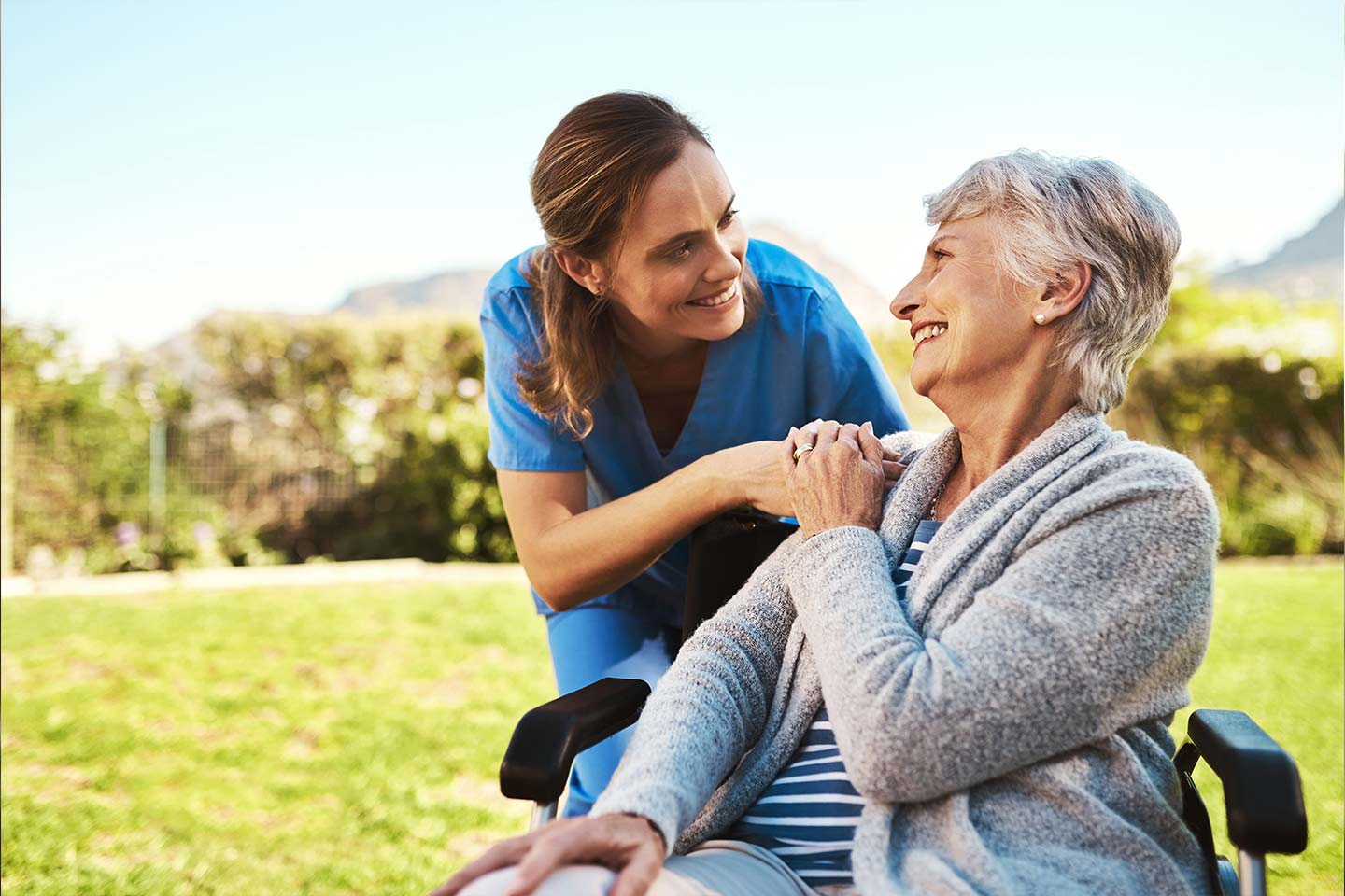 Photo of nurse warmly greeting woman in wheelchair