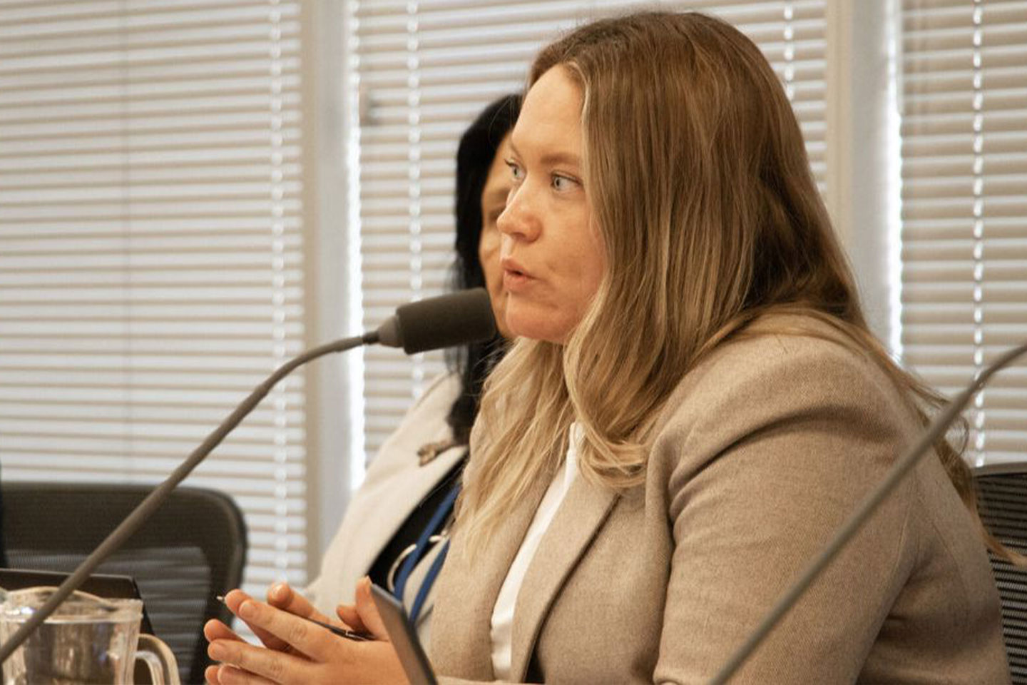 Photo of a woman in a jacket speaking into a microphone