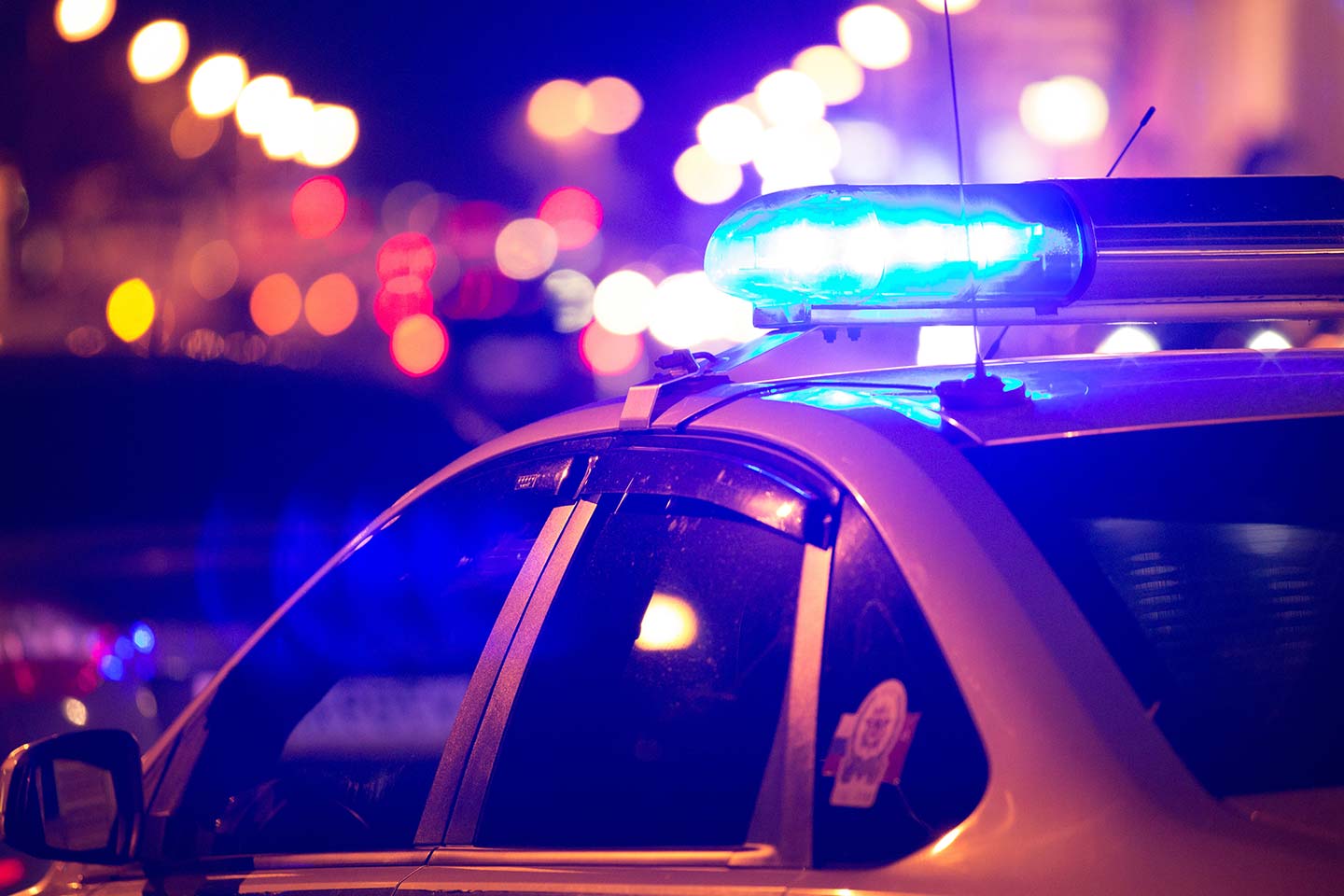 Photo of a police car with blue lights flashing at night