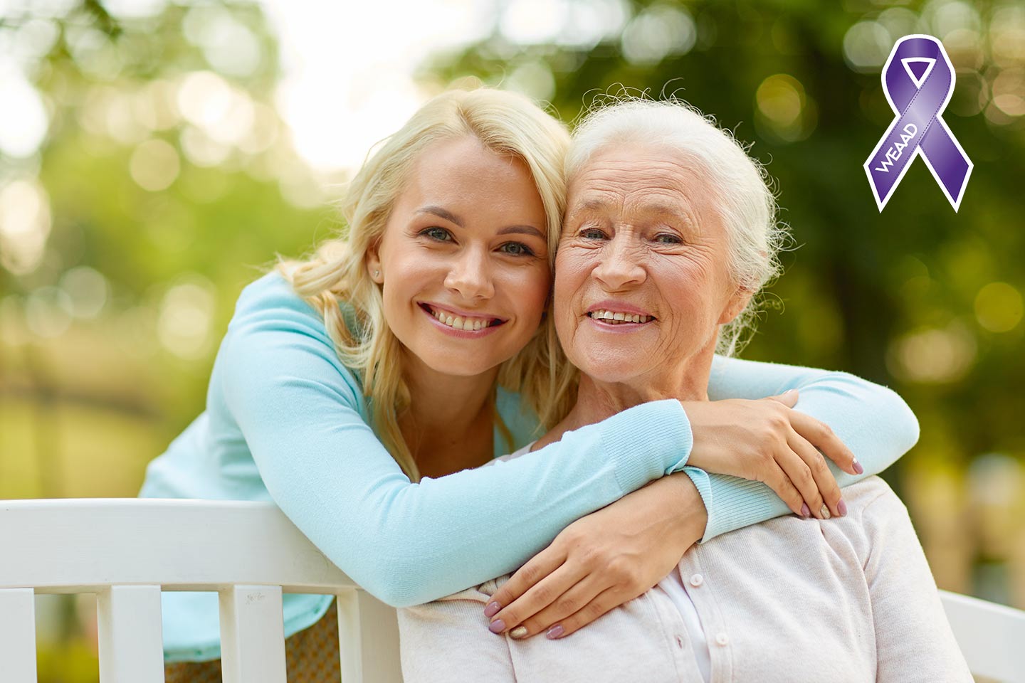 Photo of a woman in a blue cardigan embracing another woman on a park bench