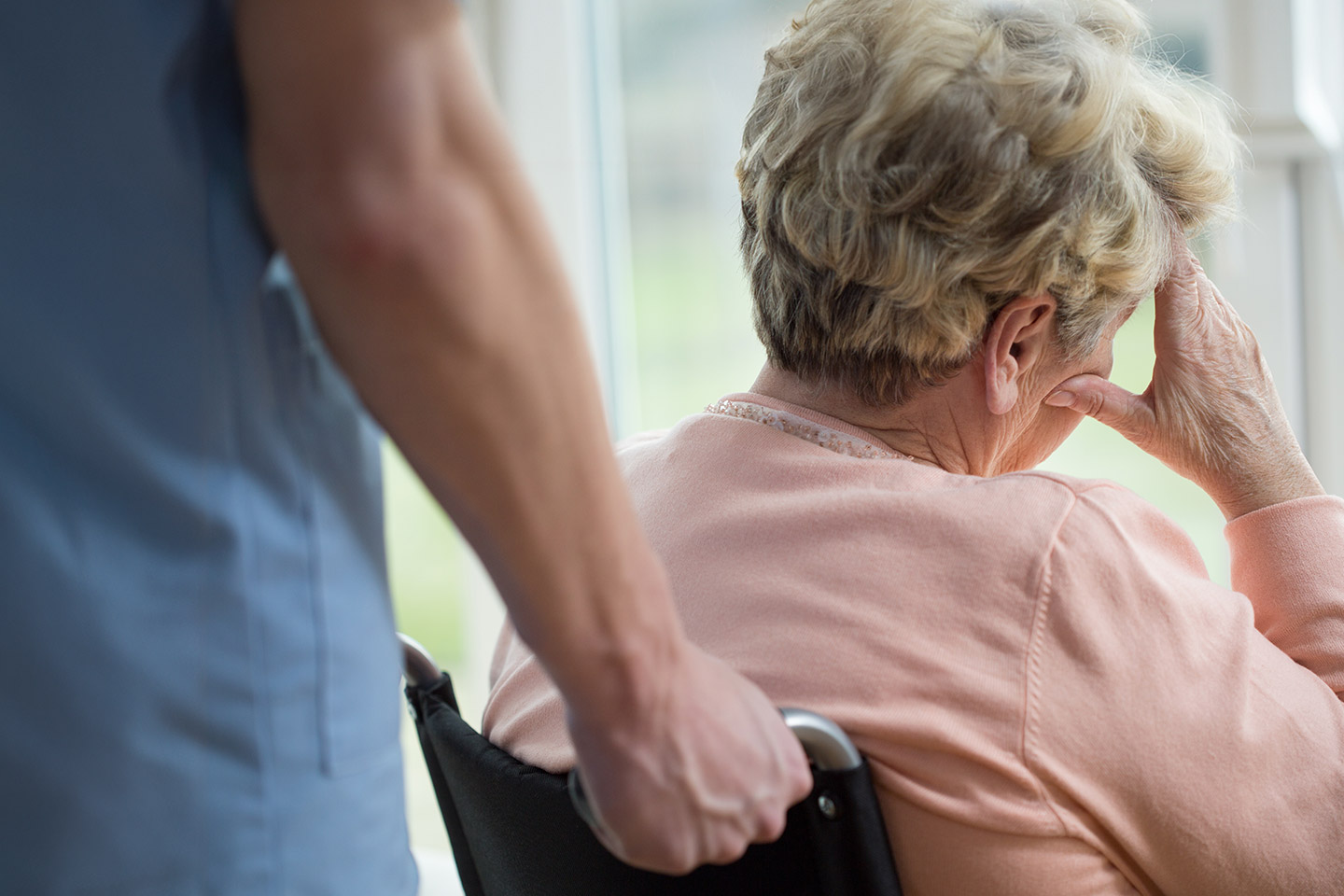 Photo of woman in pink in a wheelchair with nurse