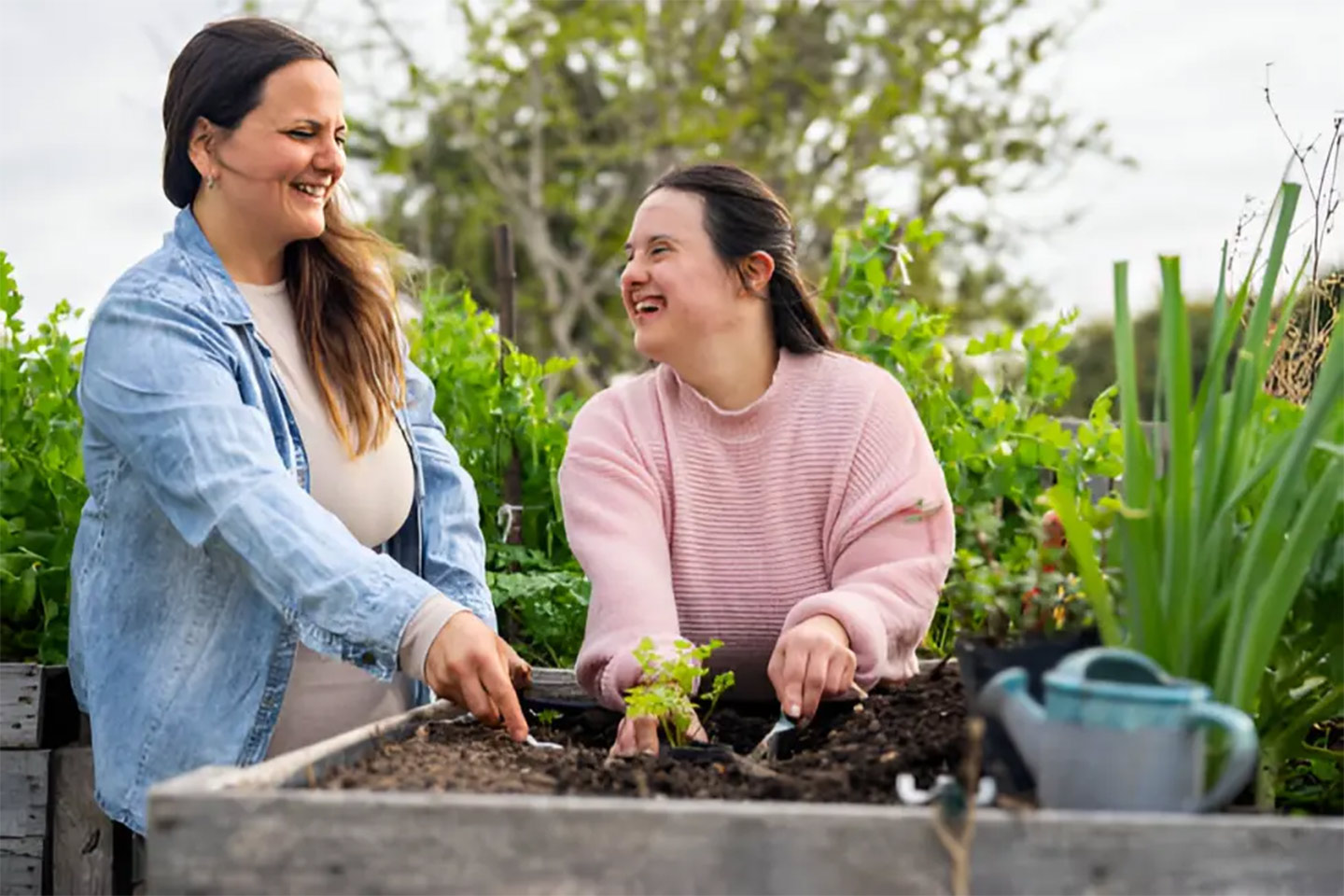 Photo of two laughing women planting in a community garden