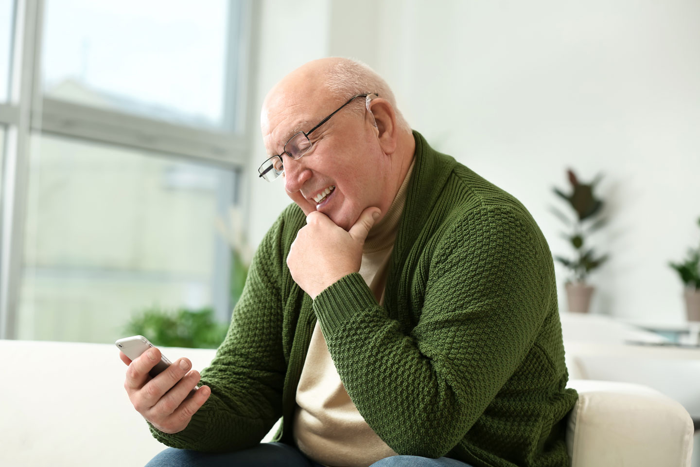 Senior man with hearing aid looking at him smart phone