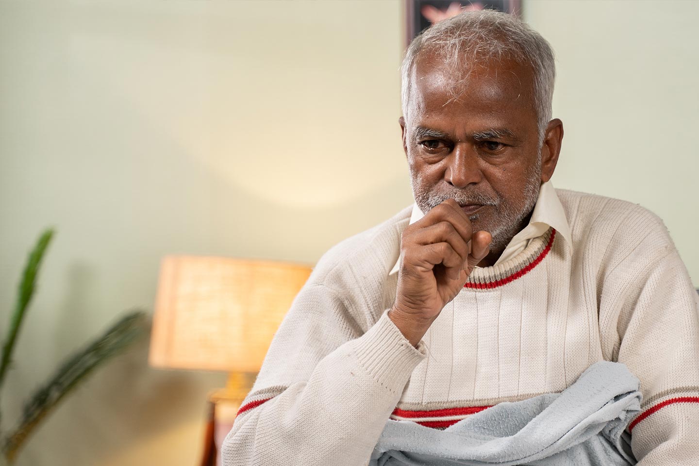 Photo of a man with his hand to his mouth in a well lit room