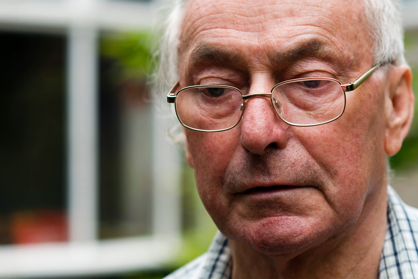 Photo of a man in a check shirt wearing spectacles