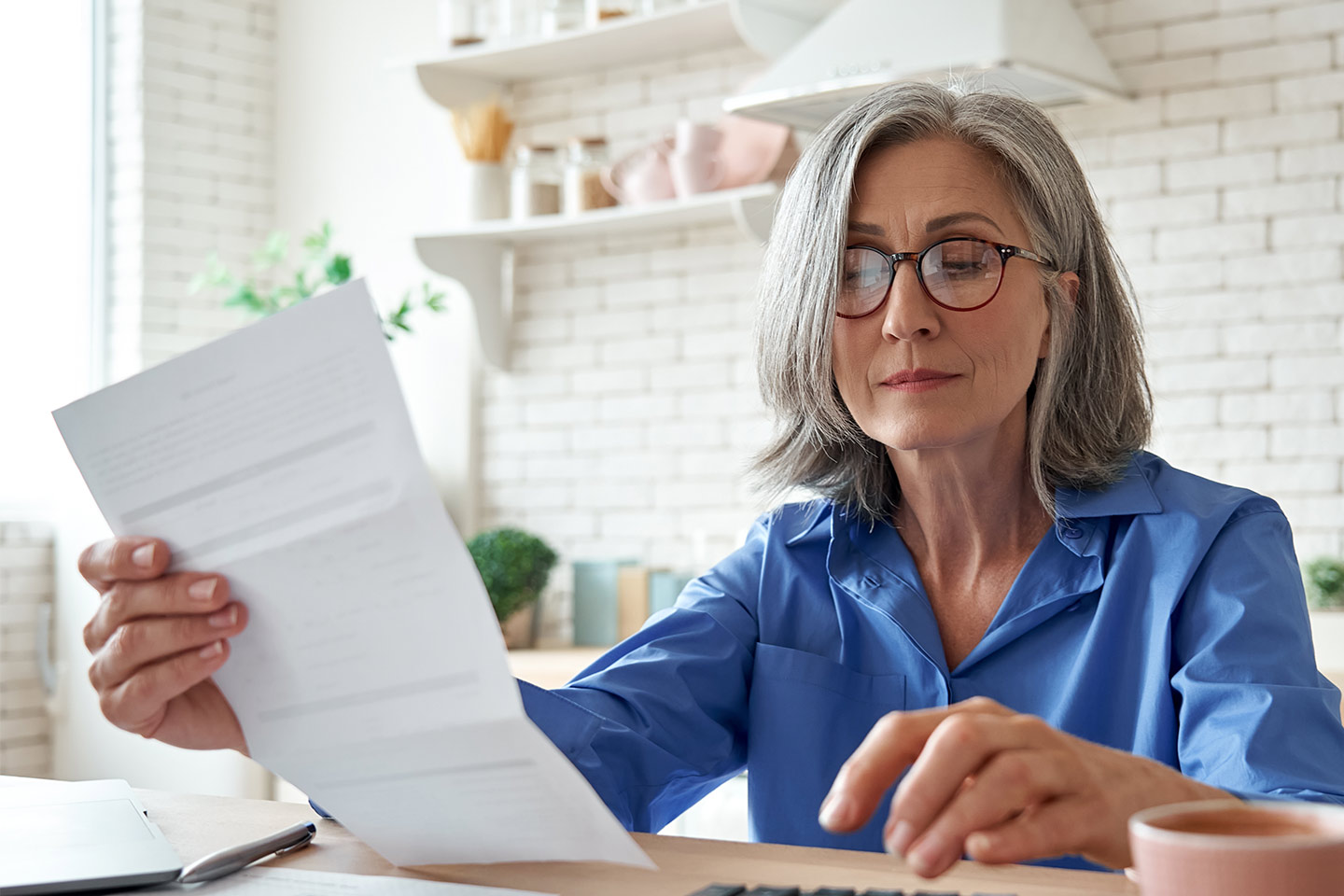Photo of a woman in a blue shirt reading through paperwork
