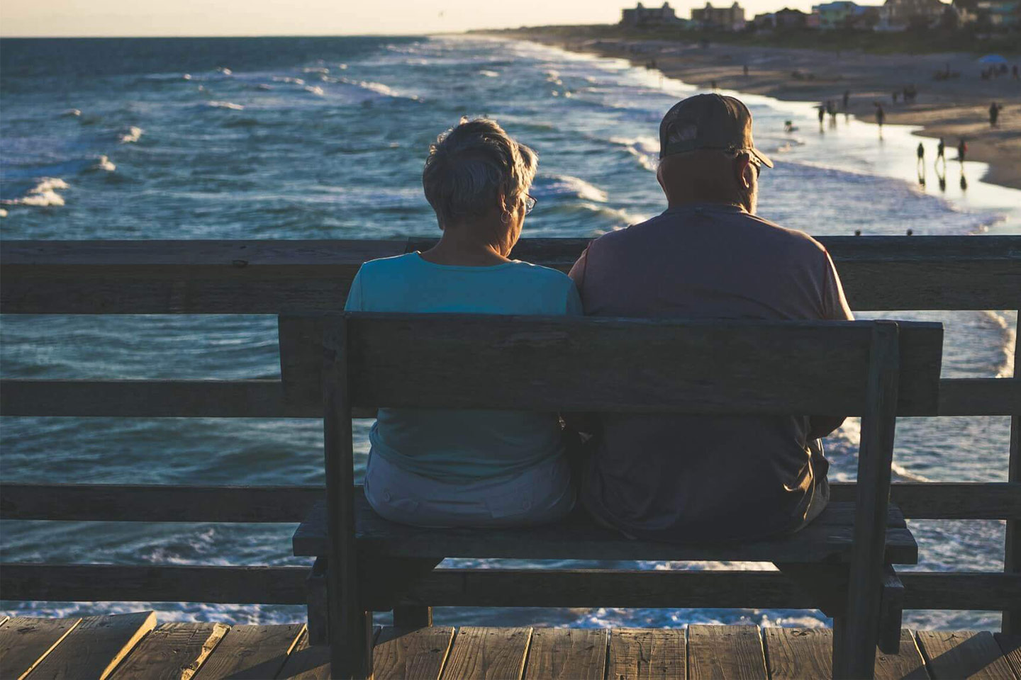 Photo of two people sitting on a bench overlooking a beach