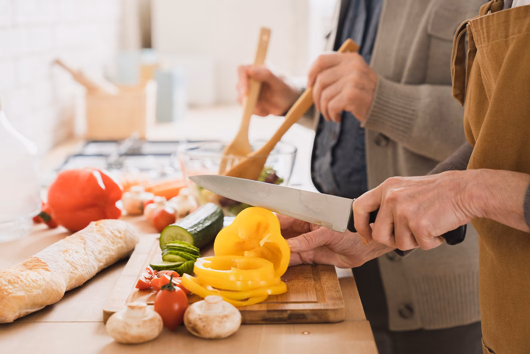 Photo of two people in a kitchen preparing vegetables