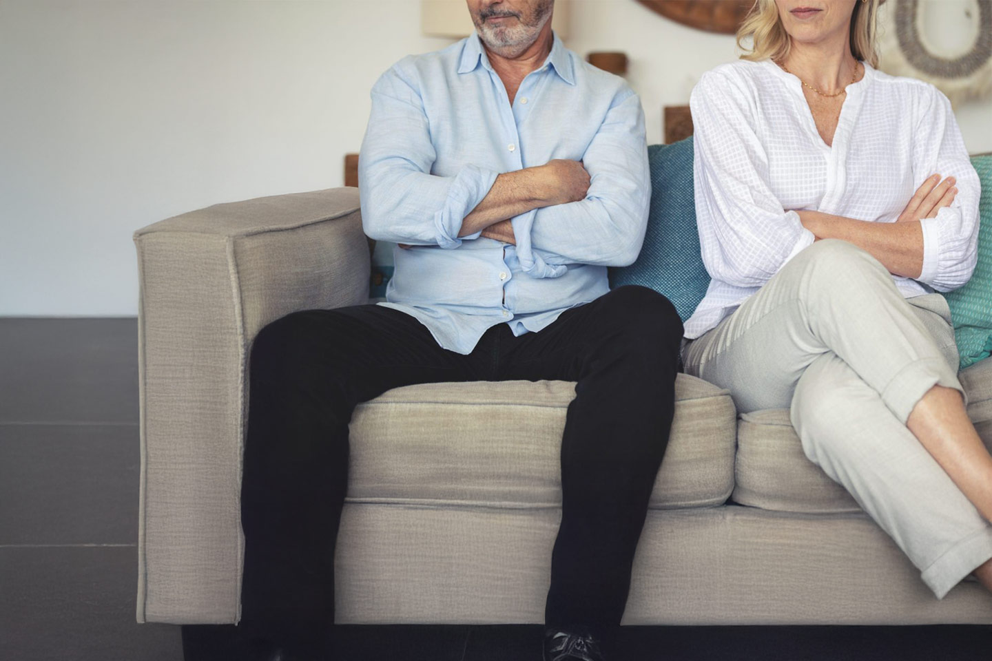 Photo of two people with crossed arms sitting on a sofa