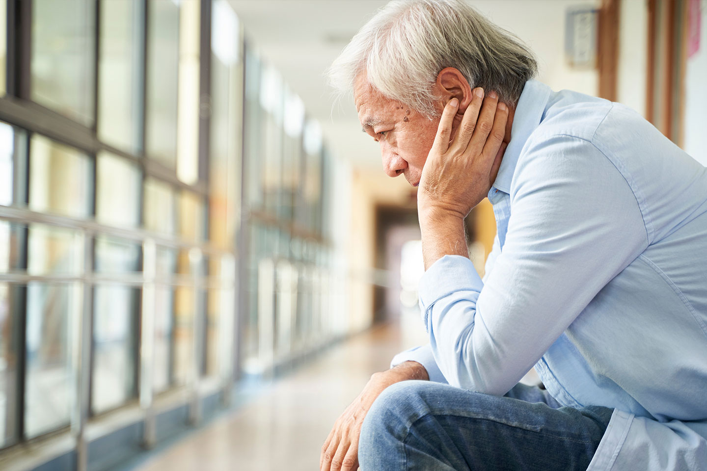 Photo of a seated man in a blue shirt and jeans