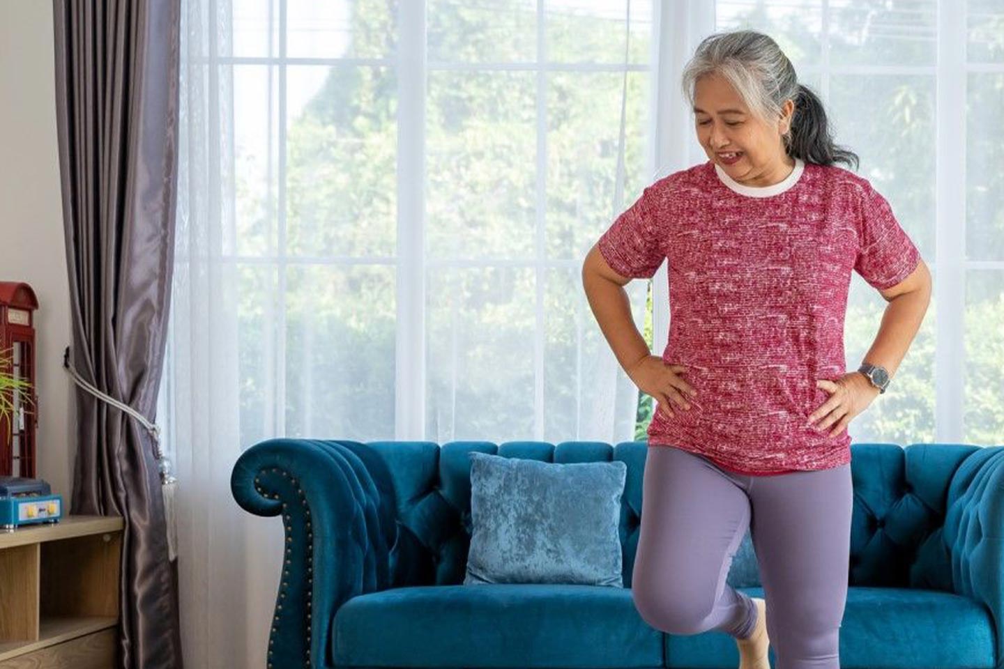 Photo of a woman standing on one leg in her lounge room