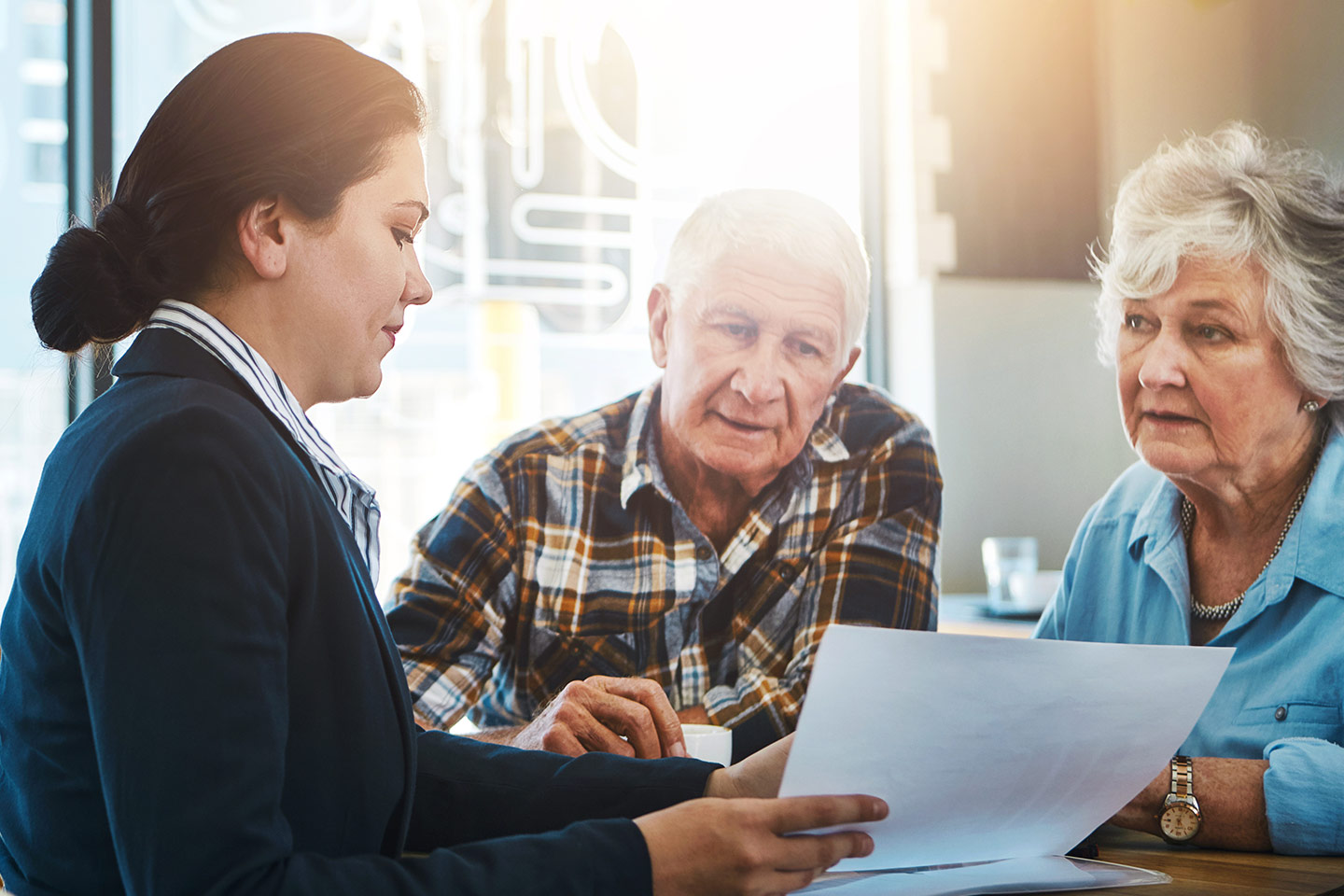 Photo of woman with a chignon showing some documents to an older couple