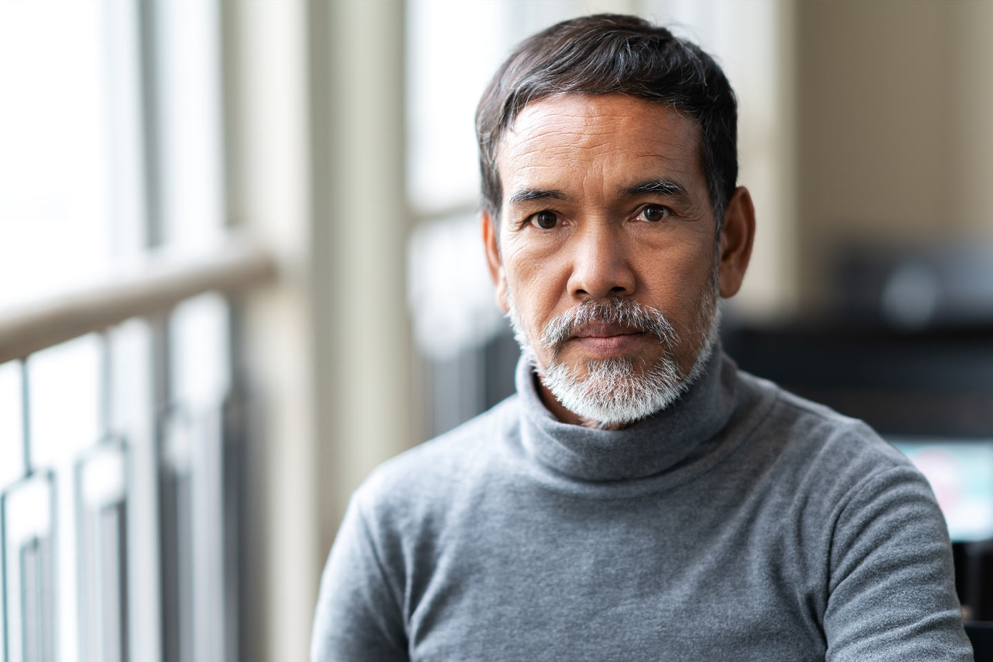Photo of a bearded man wearing a grey turtleneck