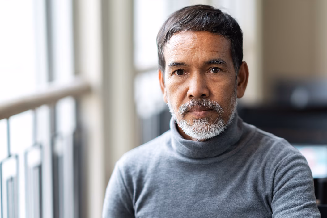 Photo of a bearded man wearing a grey turtleneck