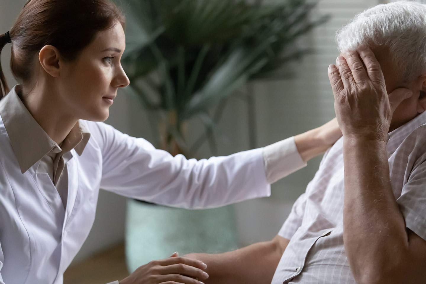 Photo of a woman comforting a man shielding his face