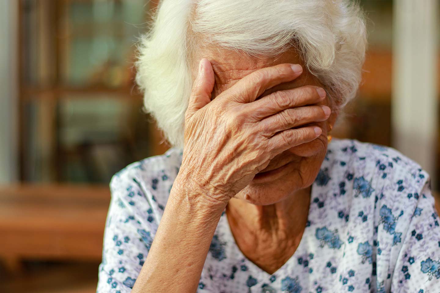Photo of woman with white hair and her hand over her eyes