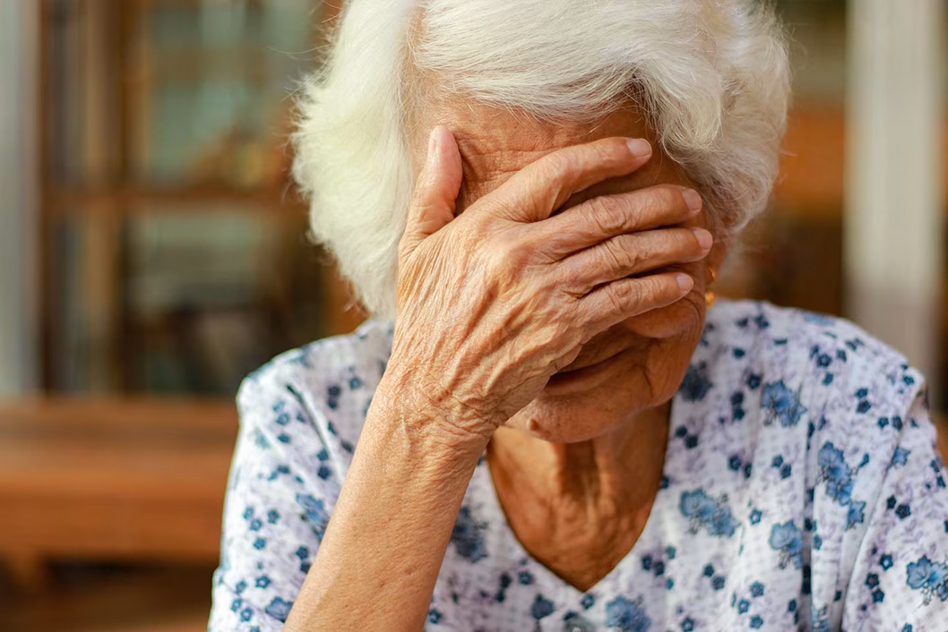 Photo of woman with white hair and her hand over her eyes