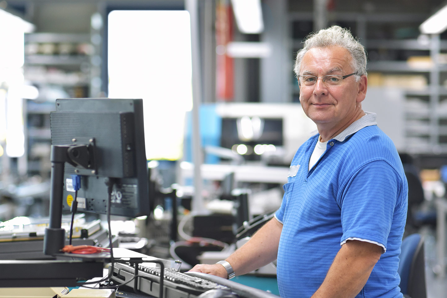 Photo of a man in a blue polo standing at a warehouse computer desk