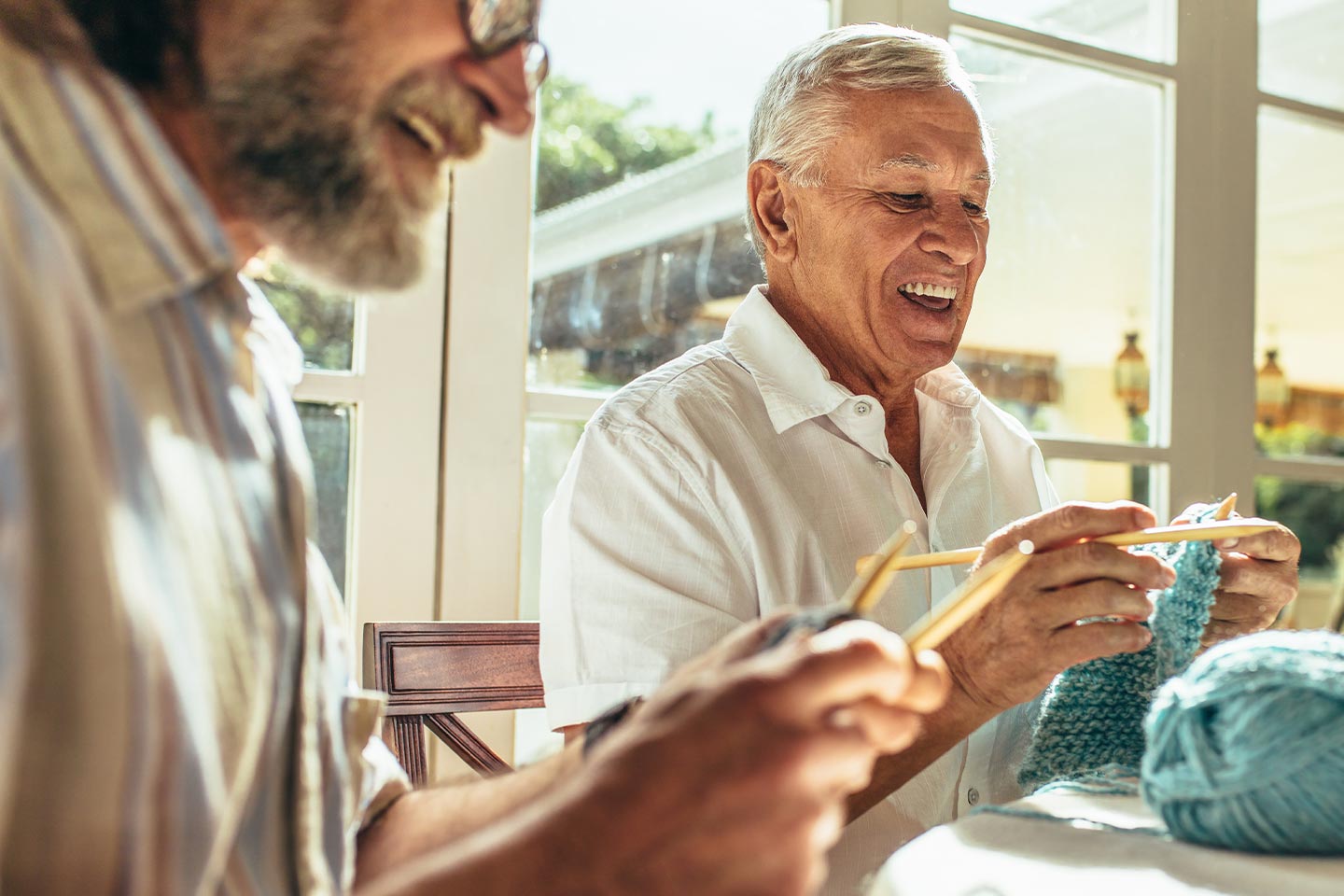 Photo of men laughing as they knit together