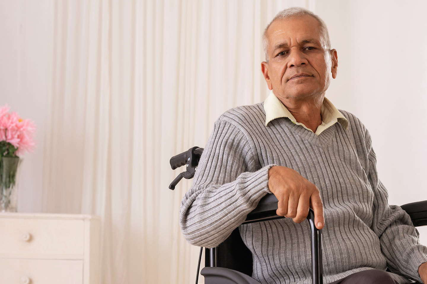Photo of a man  with a grey jumper sitting in a wheelchair