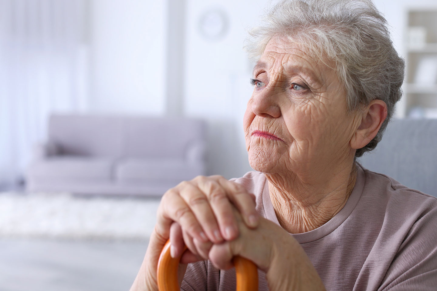 Photo of a woman with hands clasped over a walking stick