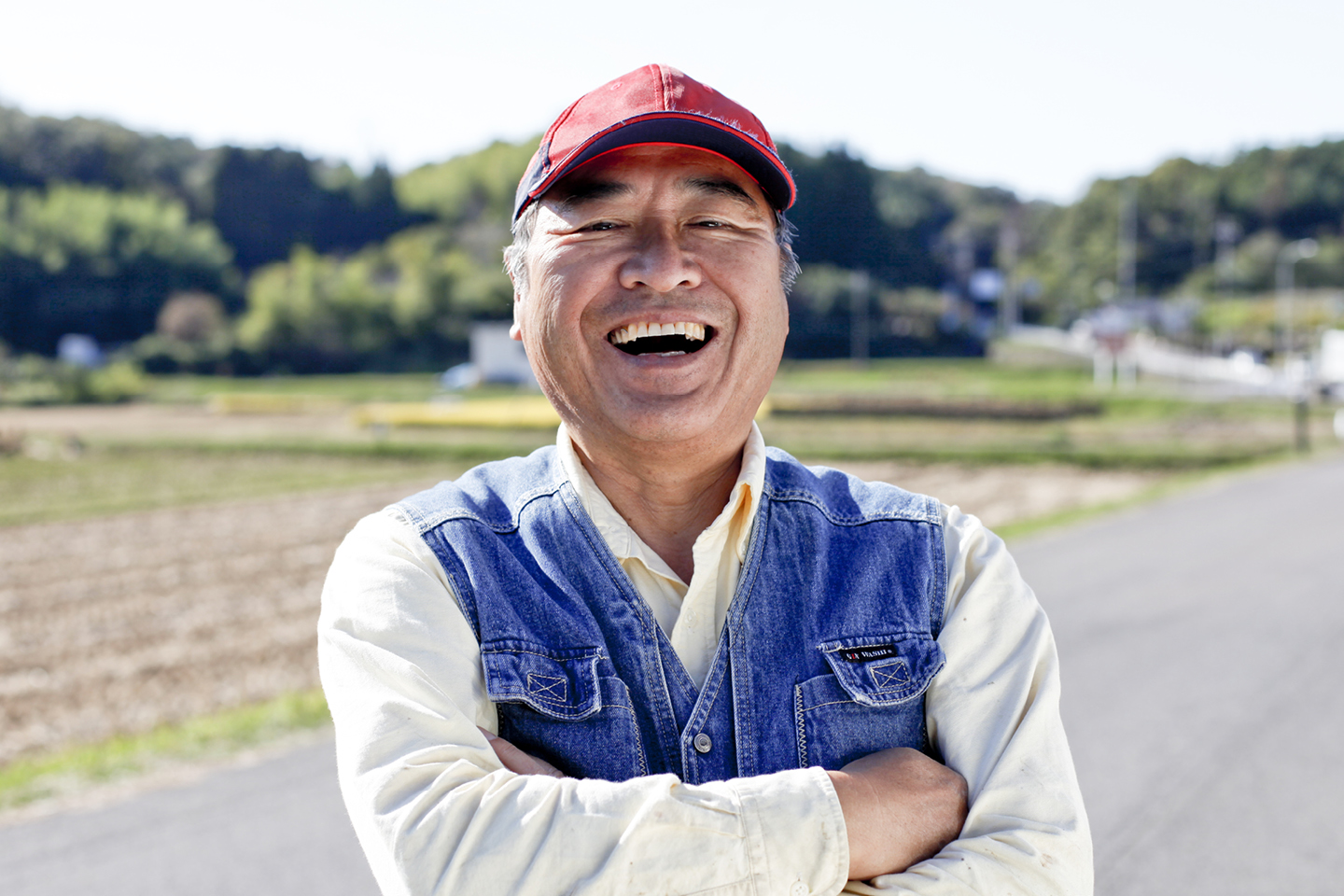 Image of a smiling Asian man wearing a red cap.