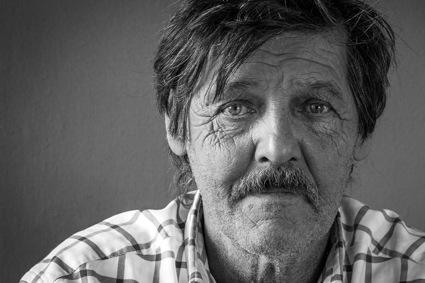 Photo of a man with a check shirt and moustache