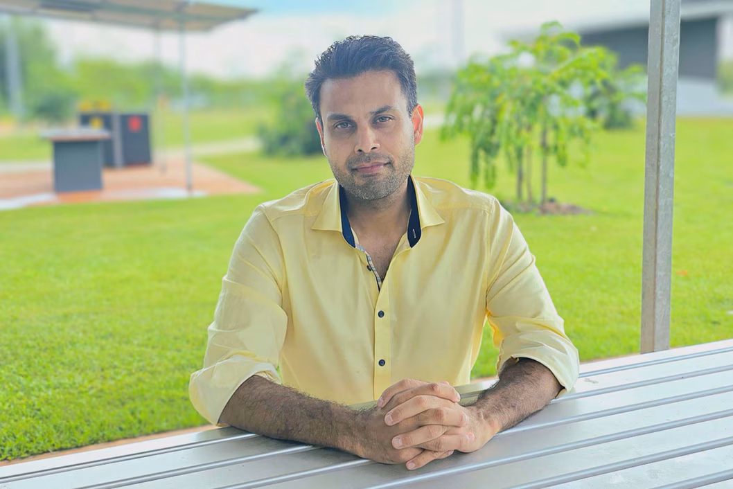 Photo of a man in a yellow shirt sitting at an outdoor table