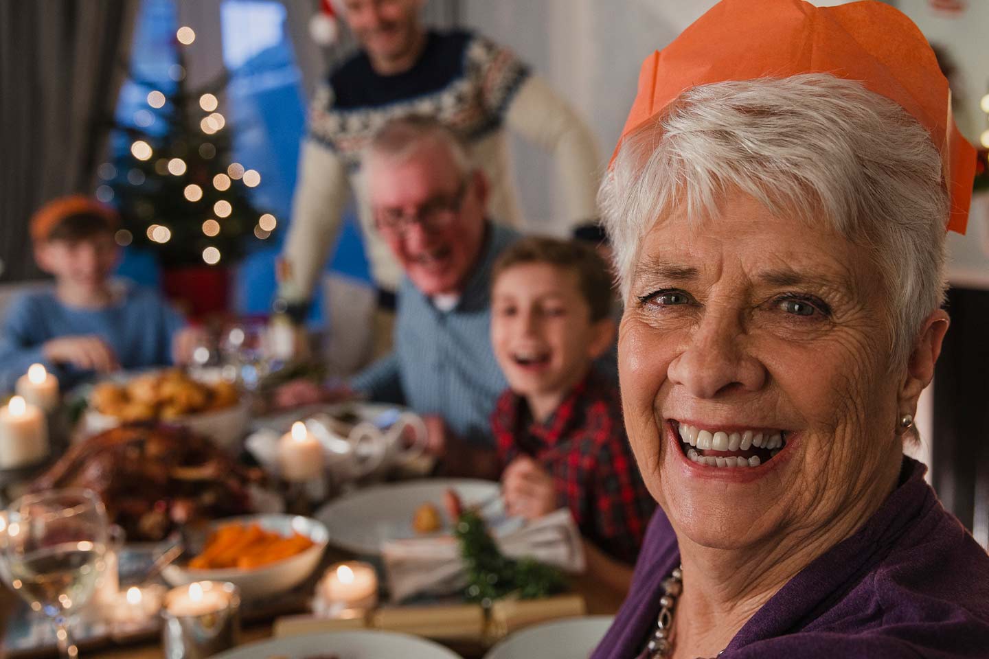Photo of a woman at a christmas dinner wearing an orange paper hat