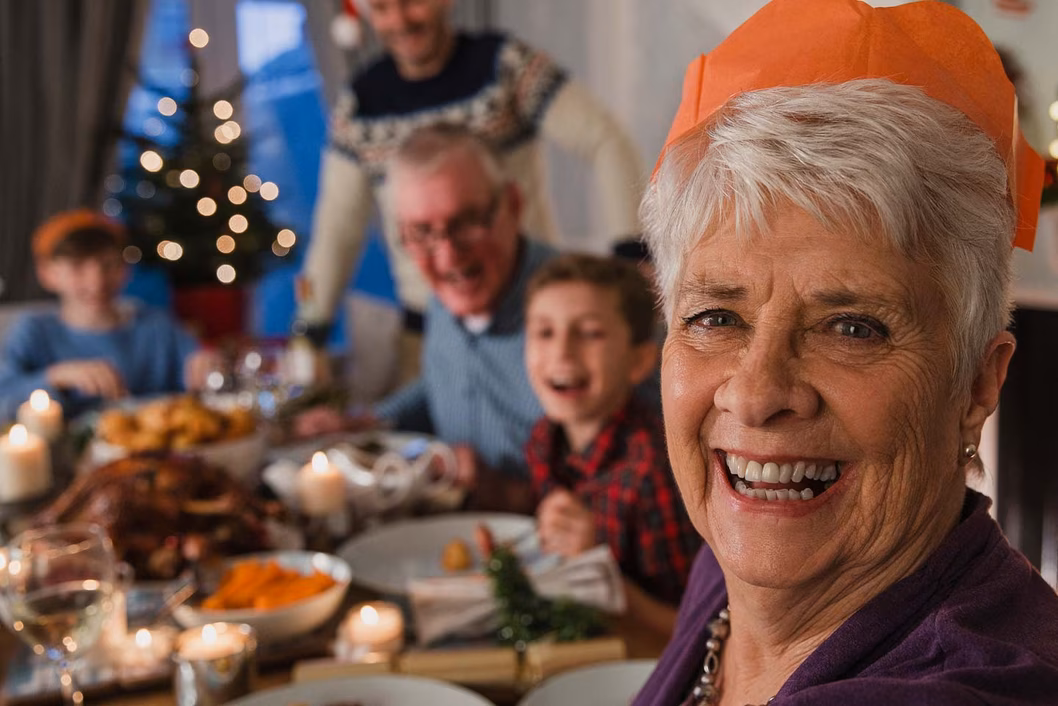 Photo of a woman at a christmas dinner wearing an orange paper hat