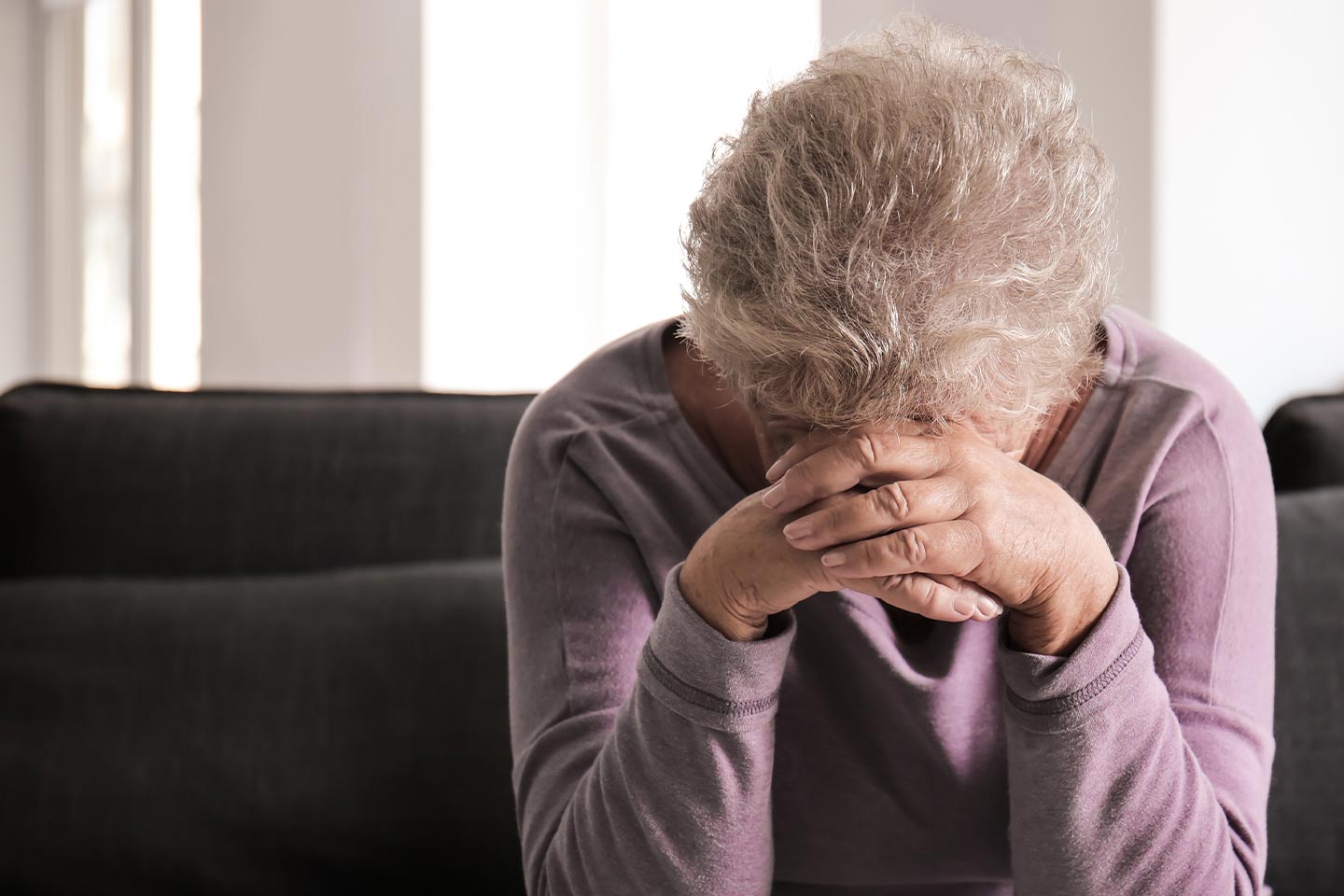 Photo of a woman in a lilac top resting her head on her hands