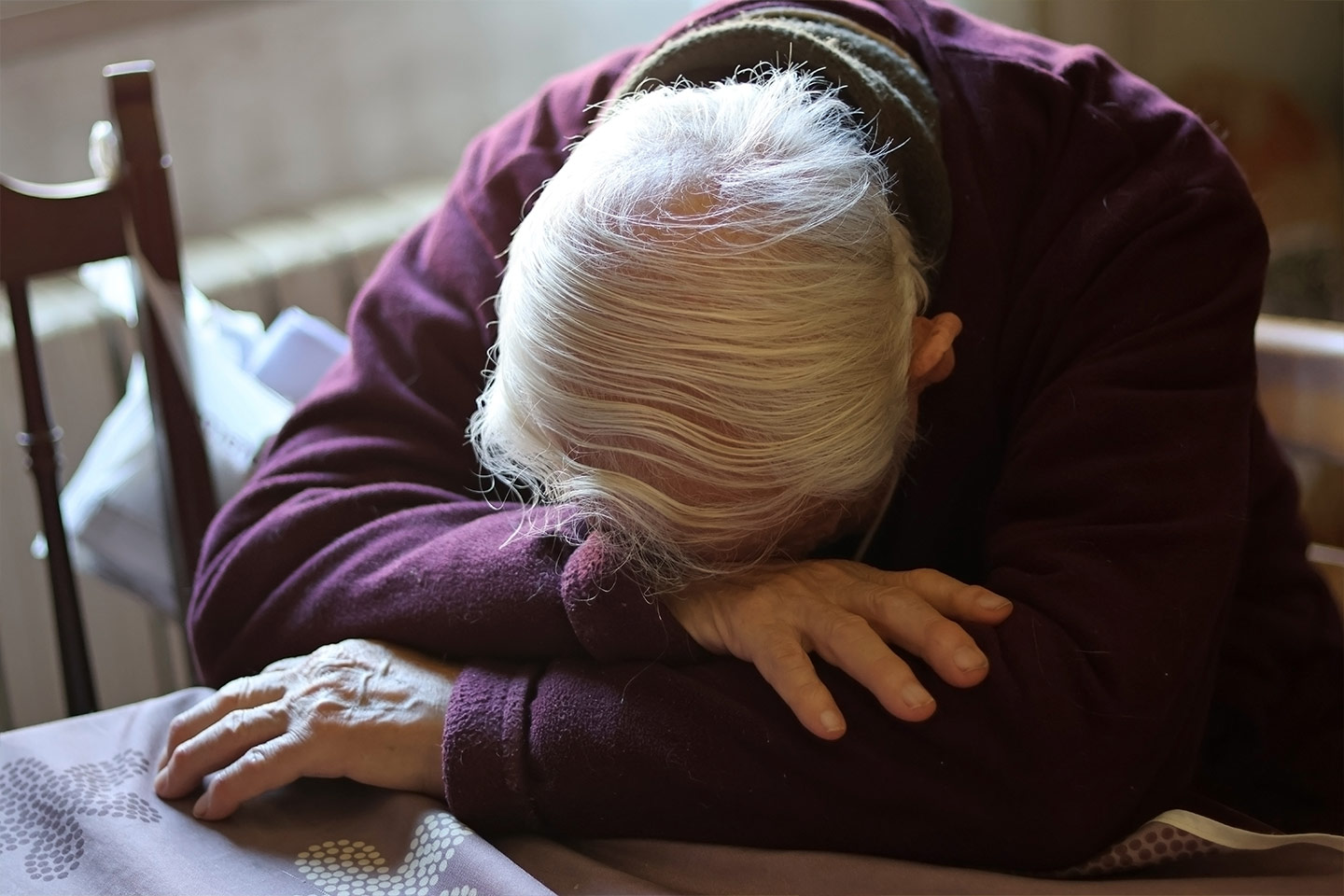 Photo of older person resting their head down on a table