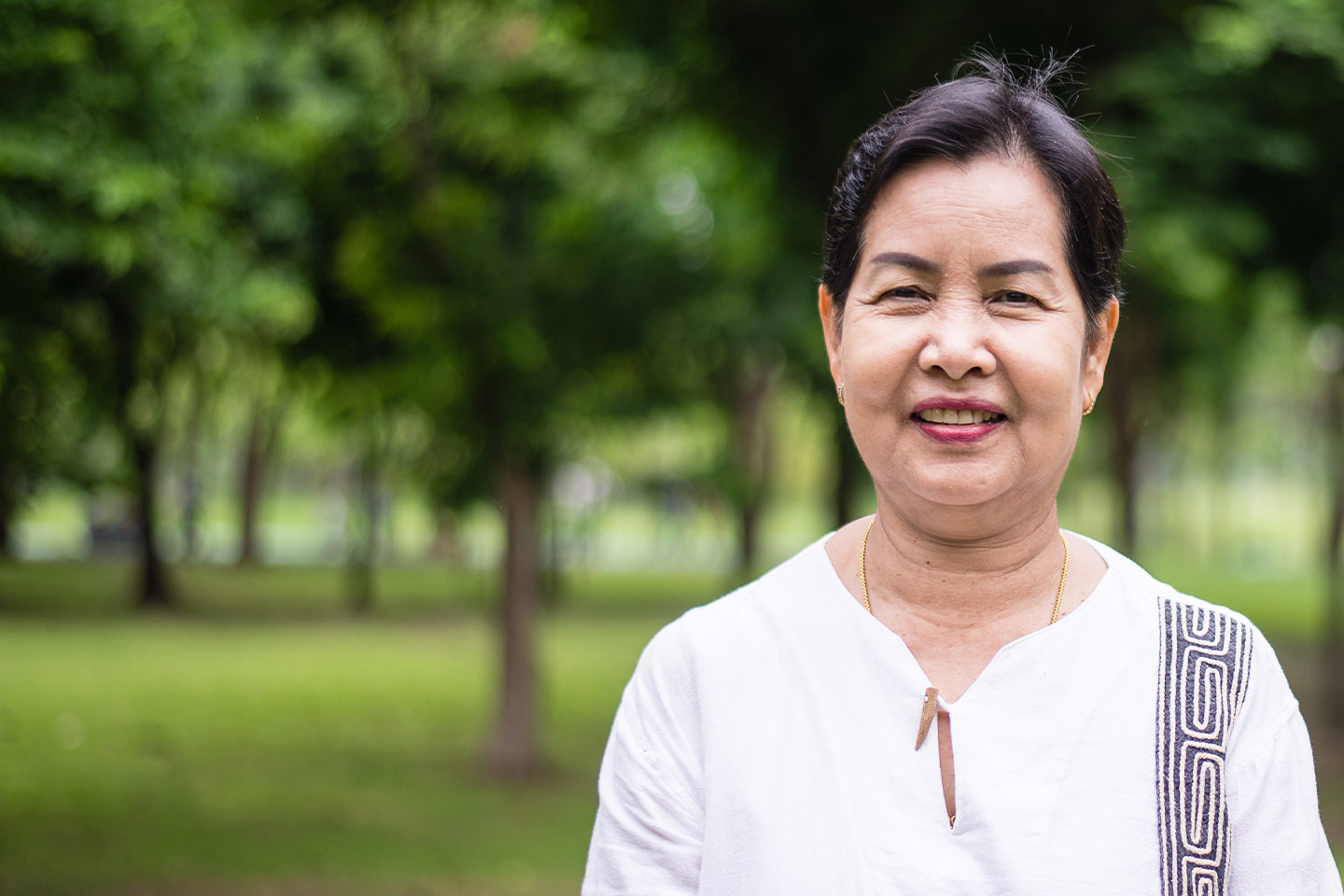 Image of an older Asian woman standing in a park