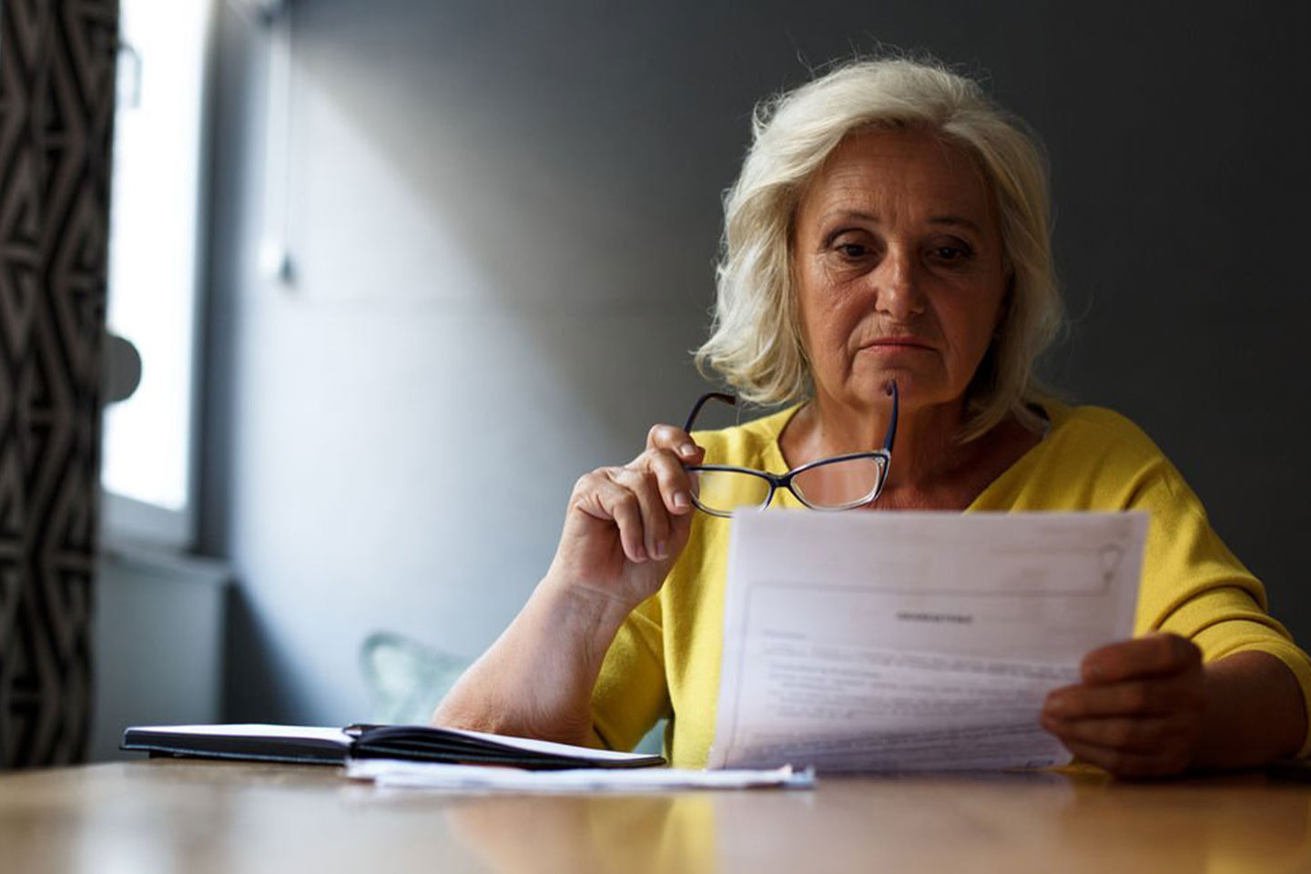 Photo of a woman in a yellow top reading a document