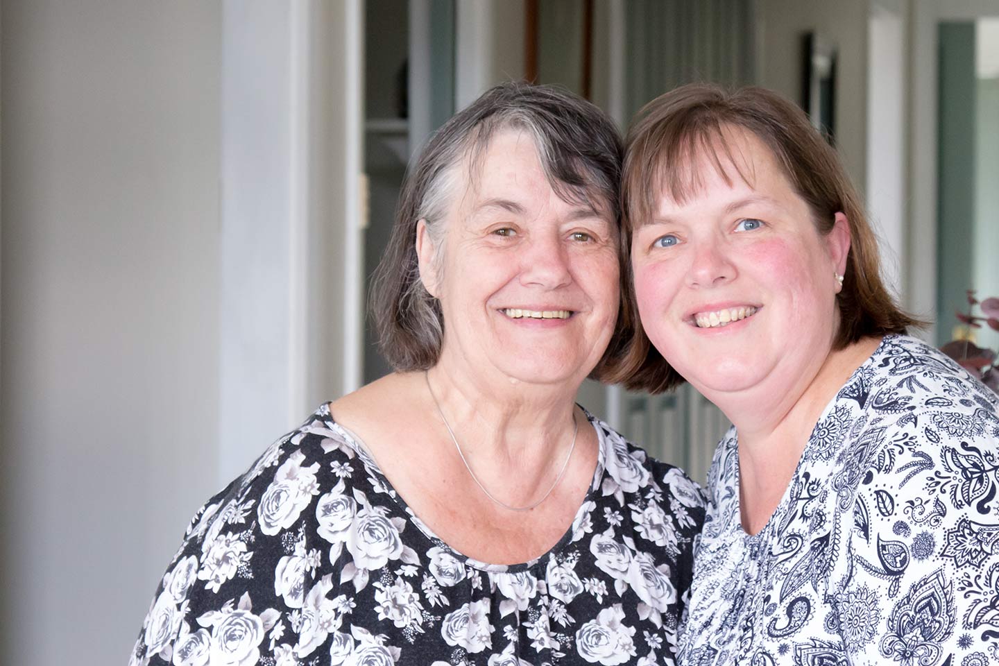 Photo of two women smiling in monochrome shirts