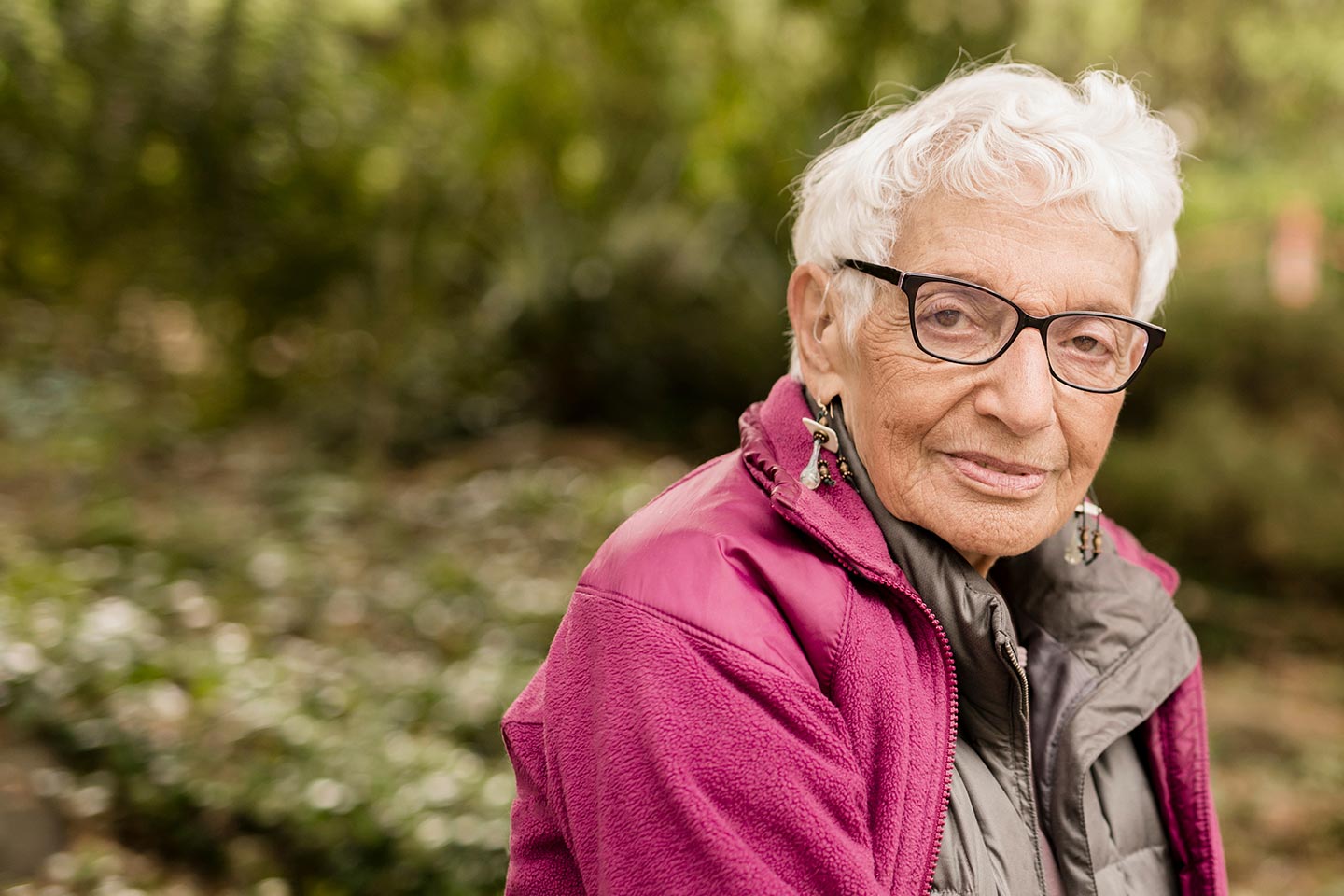 Photo of a woman in a magenta jacket sitting outside