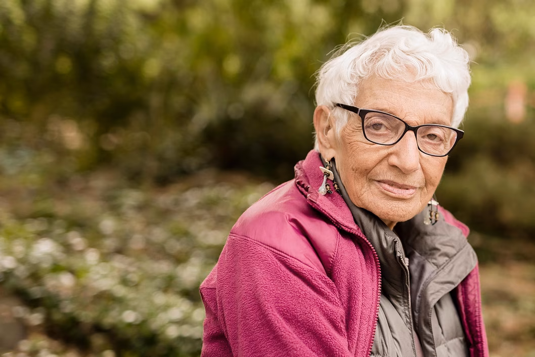 Photo of a woman in a magenta jacket sitting outside
