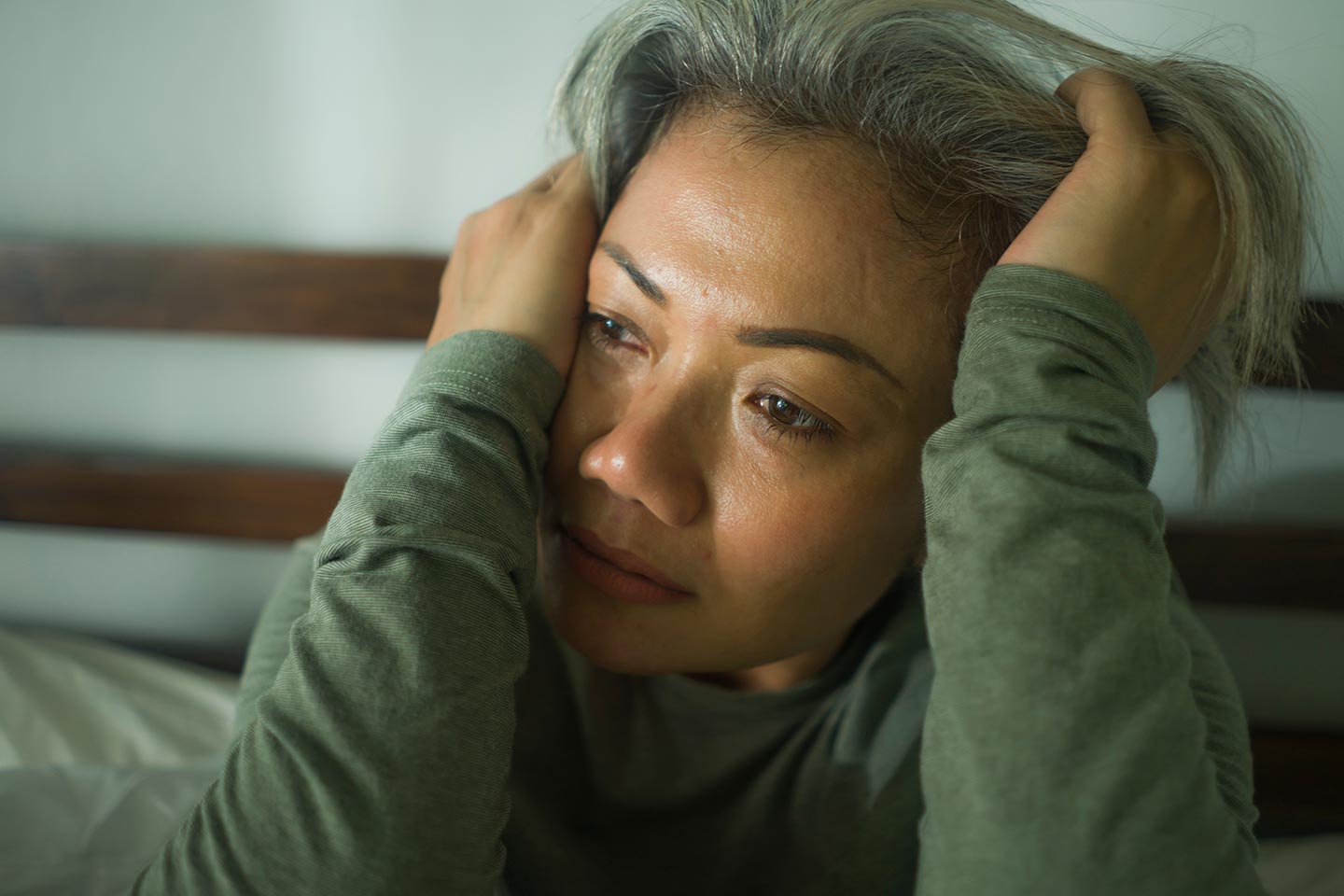 Photo of a woman in a sage green top with hands in her hair