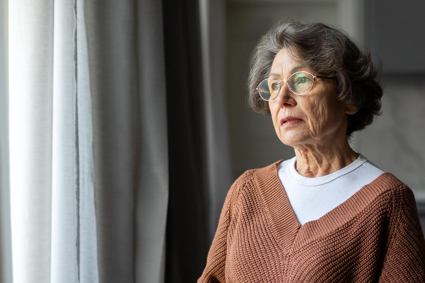Photo of woman looking pensively through window