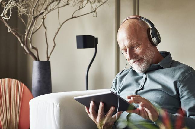 Image of an older man listening to a podcast