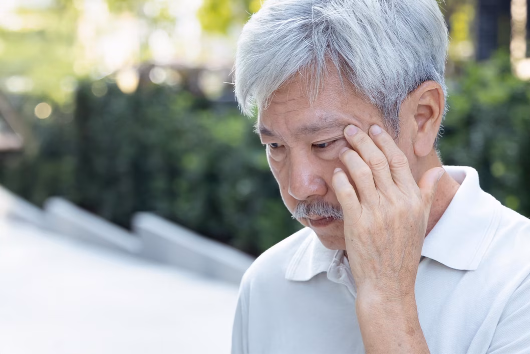 Photo of a man with a moustache with his fingers at his temples