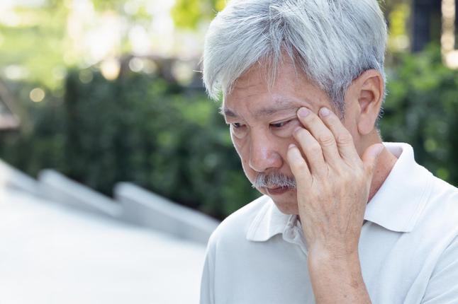 Photo of a man with a moustache with his fingers at his temples