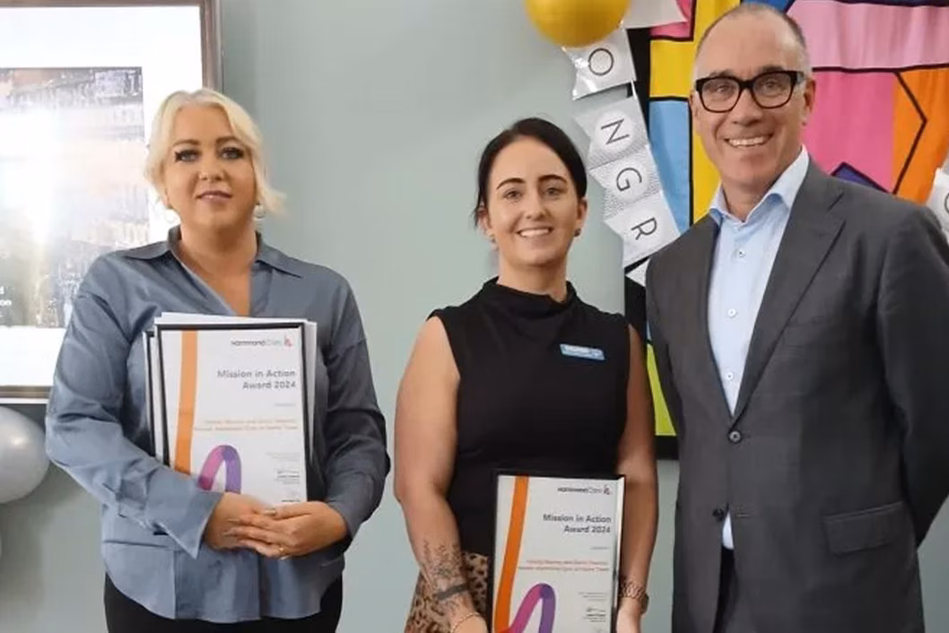 Photo of two women holding certificates standing next to a man