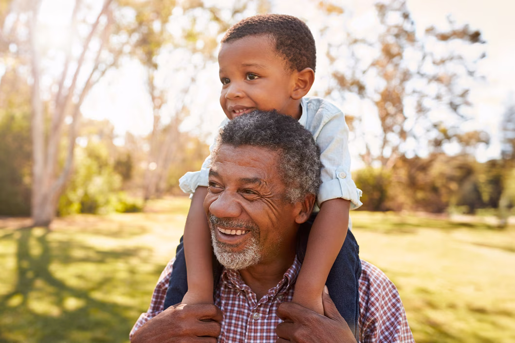 a grandfather with his grandchild on his shoulders